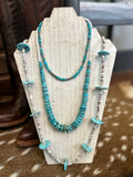 handmade turquoise necklace. bright blue turquoise necklace stack displayed on a wooden necklace display. 